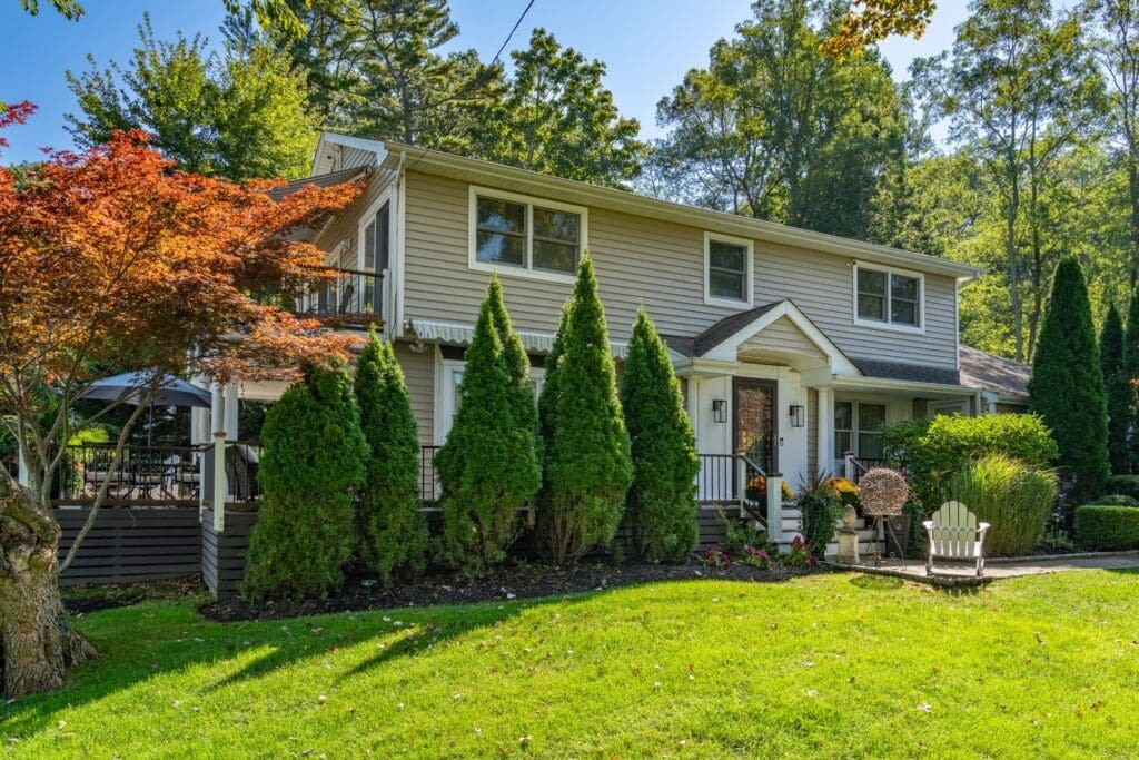 Two-story house framed by evergreen trees